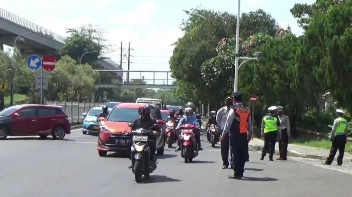 Petugas berjaga saat pemberlakukan ganjil genap di Jl Taman Mini 1 akses TMII, Cipayung, Jakarta Timur