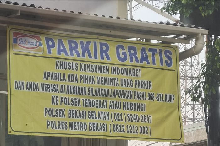 banner parkir gratis di Indomaret yang menyarankan konsumen untuk lapor polisi jika ada yang menarik pungutan
