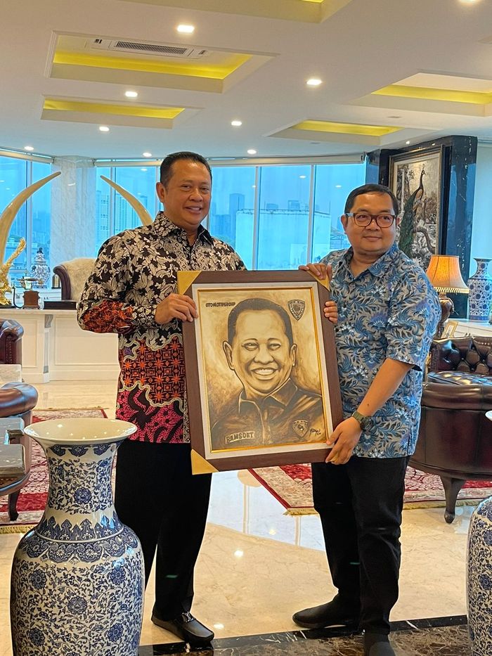 Bambang Soesatyo selaku Ketua PP IMI menerima kenang-kenangan lukisan kopi bergambar dirinya dari Group Editorial Director Otomotif Group Billy Riestianto