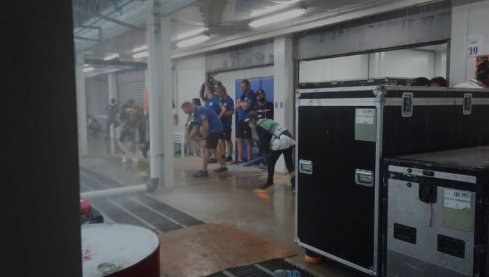 Kru tim ikutan ngepel area paddock yang terkena air hujan