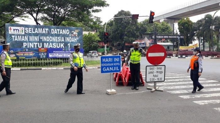 Petugas memasang plang ganjil genap di kawasan pintu utama TMII, Cipayung, Jakarta Timur