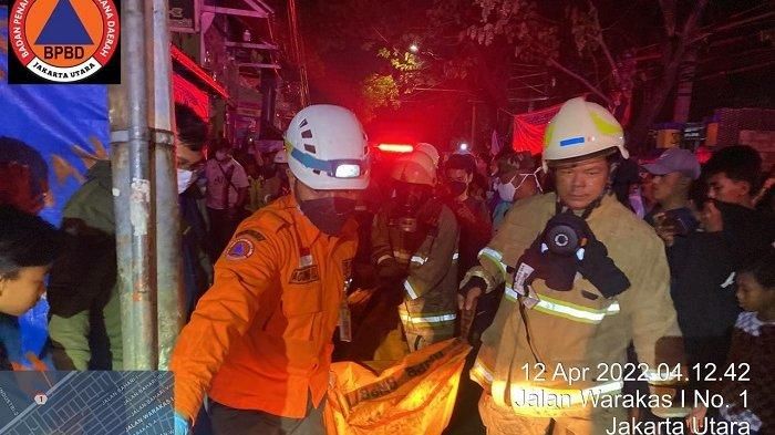 Potret sejumlah petugas damkar yang mengevakuasi korban kebakaran bengkel di Jalan Warakas, Selasa (12/04/2022).