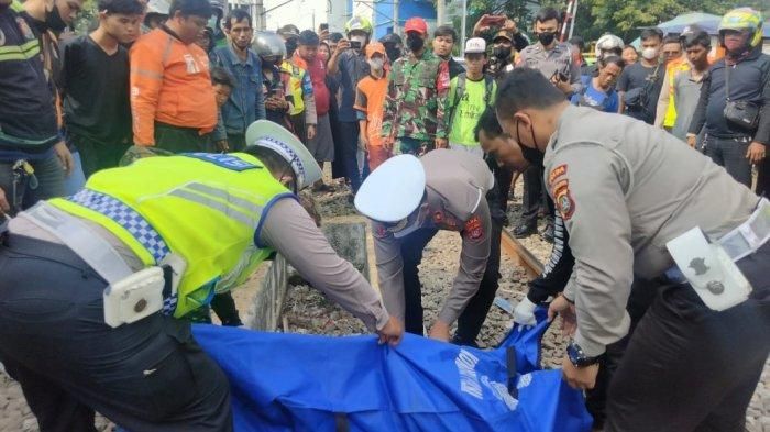 Petugas mengevakuasi jenazah AG (60), pengemudi ojol yang tewas tertabrak kereta di Jalan Mangga Dua Raya, Sawah Besar, perbatasan Jakarta Utara dan Jakarta Pusat, Senin (5/12/2022).