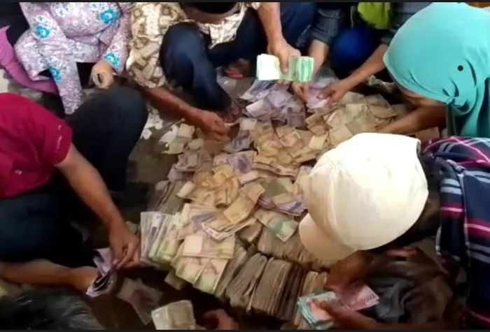 Warga tengah menghitung uang di dalam tas Minan yang ditemukan meninggal dunia di depan SPBU di Jalan Grogol, Limo, Depok.