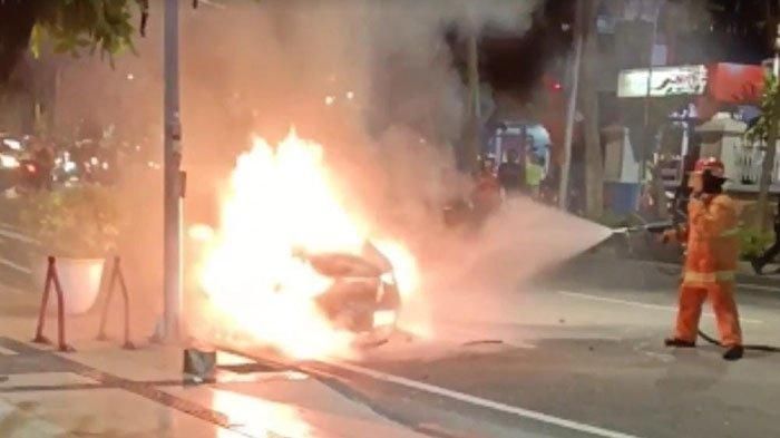 Petugas DPKP memadamkan api yang membakar mobil Honda Brio bernopol L-1283-ACA di Jalan Genteng Kali Kota Surabaya, pada Selasa (2/5/2023) malam. 