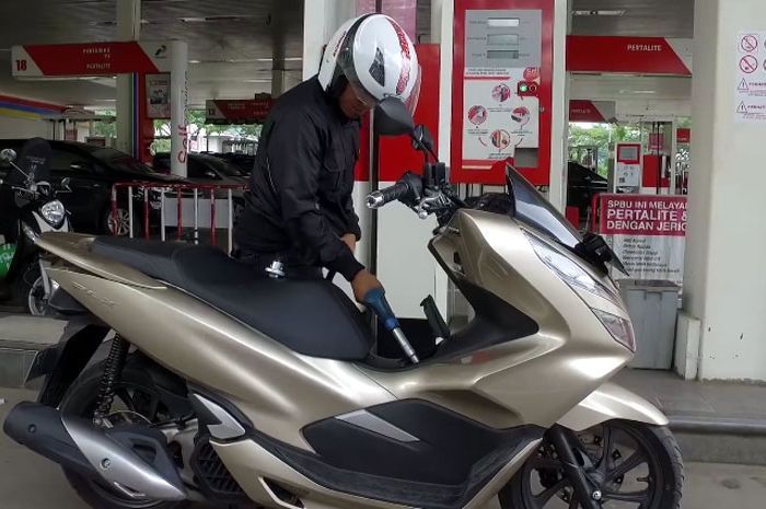 Pengendara Honda PCX turun dari motor saat isi bensin