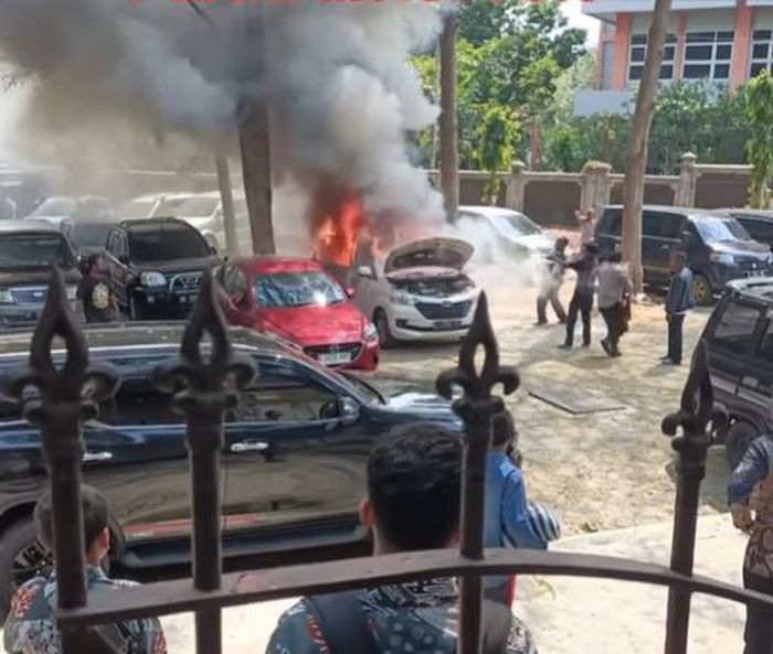 Warga dan petugas berusaha memadamkan api yang membakar Toyota Avanza di parkiran kampus ISI Solo menggunakan APAR