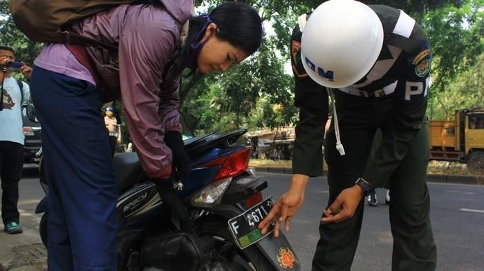Polisi Militer melepas stiker TNI yang terpasang di pelat nomor motor warga sipil