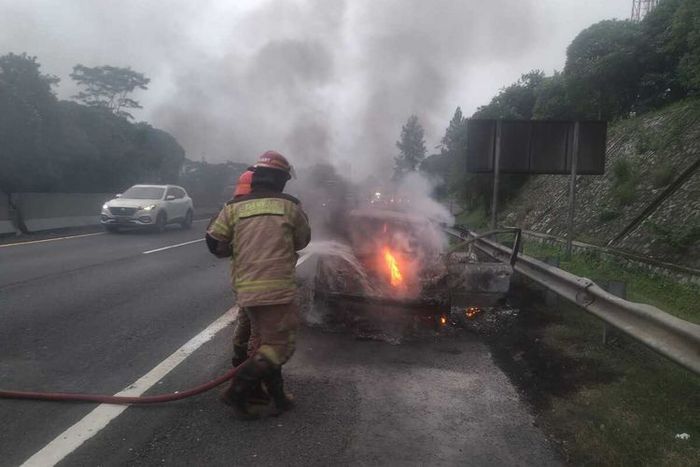 Petugas pemadam kebakaran berusaha memadamkan api yang membakar Peugeot 206 di KM 99 tol Cipularang