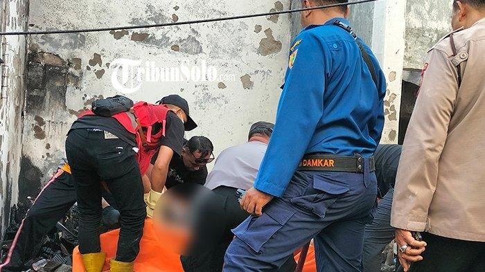 Petugas mengevakuasi jasad pria tertelungkup dari dalam bangunan toko yang terbakar di Ngrampal, Sragen, Jawa Tengah