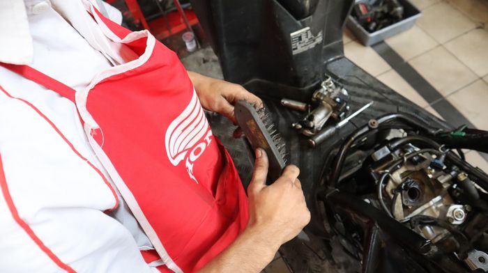 Proses pembersihan busi motor menggunakan sikat kawat