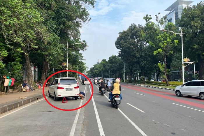 Pemilik mobil mengganti roda sendiri setelah ban-nya digembosi petugas Dishub ketika parkir di Jalan Medan Merdeka Selatan, Gambir, Jakarta Pusat, (29/12/24)