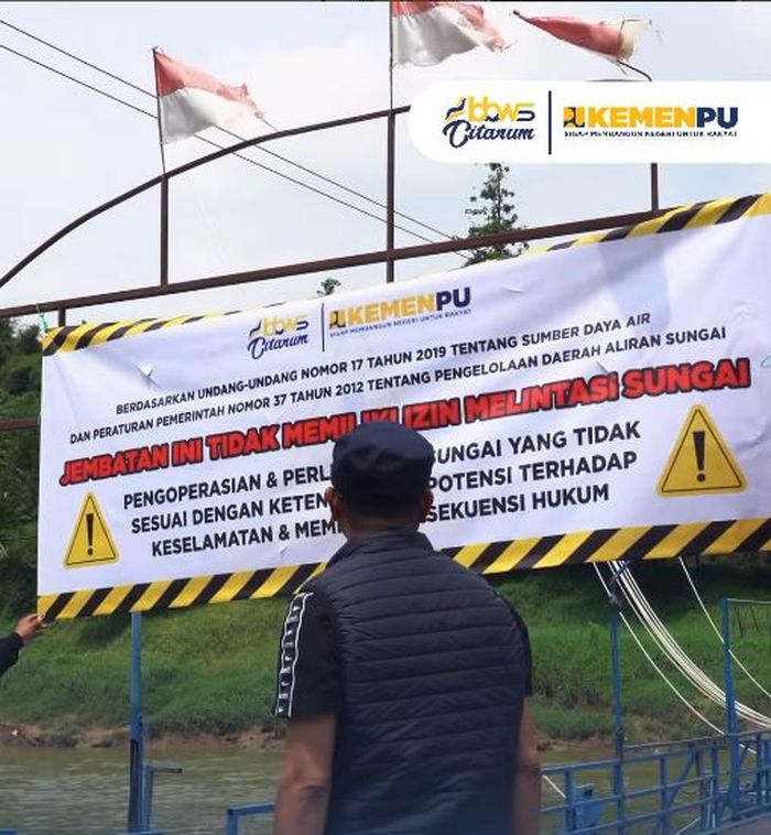 Spanduk peringatan dari BBWS Citarum di jembatan apung Haji Endang, bertuliskan nada ancaman setelah 15 tahun berdiri