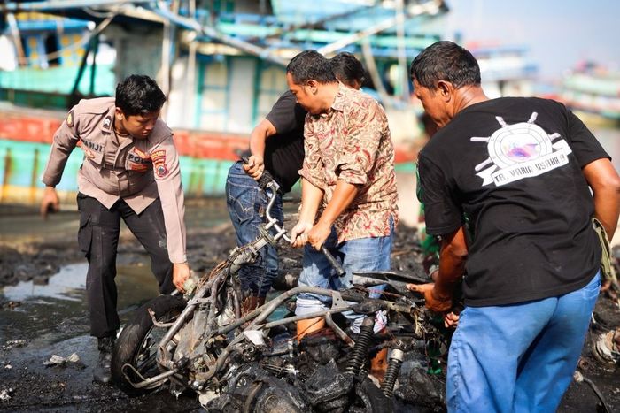 Petugas dan warga memindahkan bangkai motor yang terbakar di dermaga pelabuhan Pelindo kota Tegal