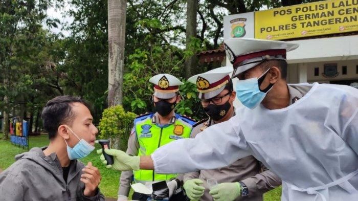 Polisi melakukan tes kadar alkohol terhadap seorang pengendara motor menggunakan alat breathlyzer