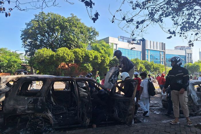 Penjarah mempreteli besi dan part bangkai mobil-mobil yang dibakar dekat markas Brimob Kwitang, Jakarta Pusat