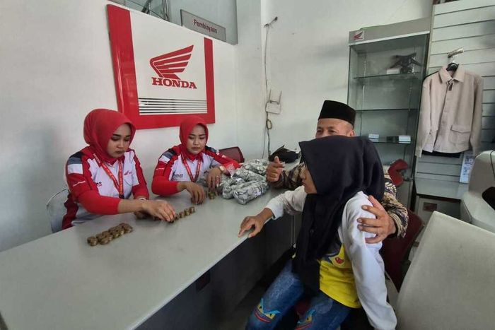 Karyawati dealer motor Honda menghitung empat karung dan satu kardus uang koin yang dibawa Sunarta (51) bersama anaknya untuk beli motor matic