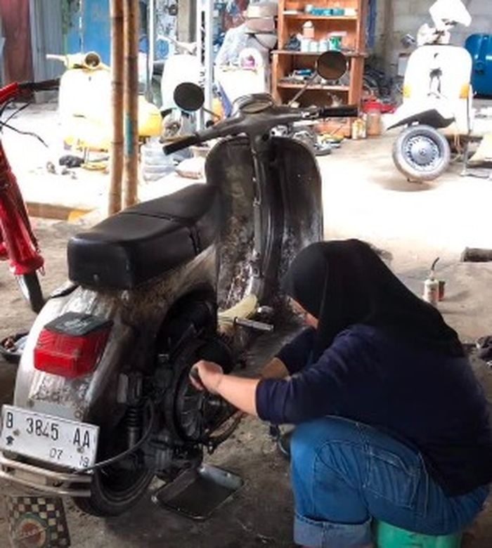Syahrina sedang memperbaiki Vespanya 