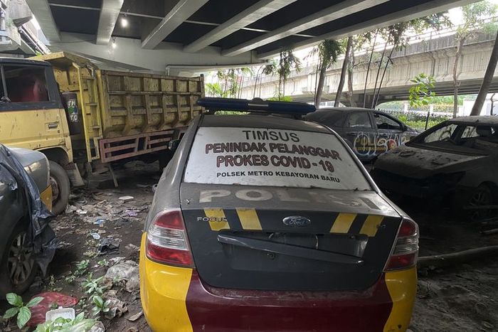 Ford Focus yang masih menyisakan stiker bertuliskan 'TIMSUS PENINDAK PELANGGAR PROKES COVID-19 POLSEK METRO KEBAYORAN BARU' di kolong flyover Tanjung Barat, Jakarta Selatan