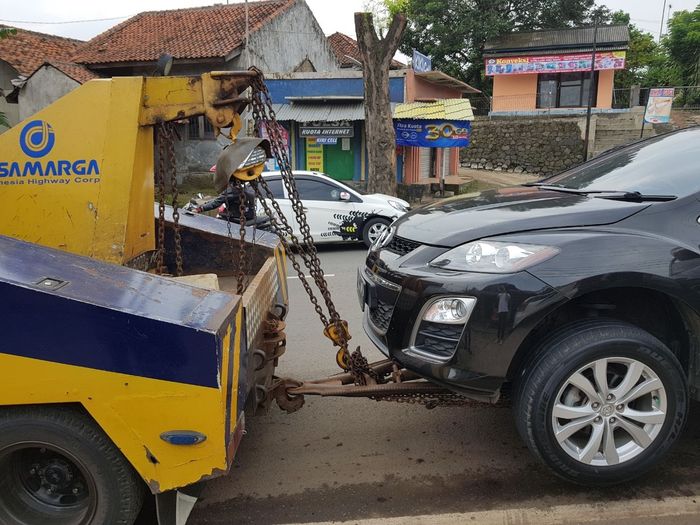 Ilustrasi truk derek membawa mobil di tol