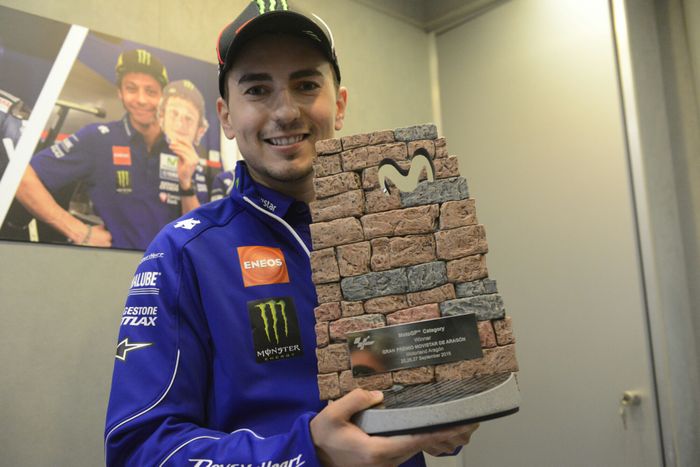 Jorge Lorenzo memegang trofi berbentuk tumpukan batu menyerupai dinding di sirkuit Aragon