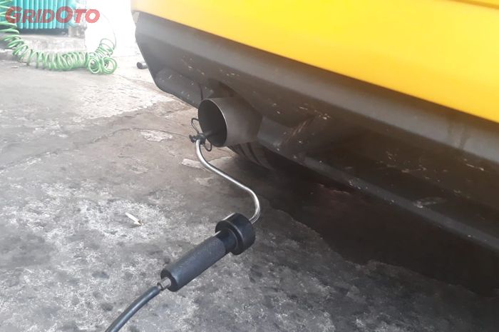 Pembaca alat uji emisi dimasukkan ke knalpot mobil 