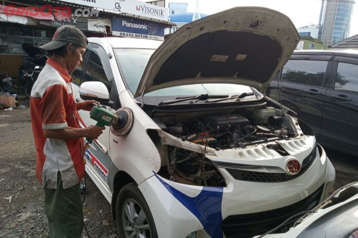 Salah satu mekanik body repair Karya Motor di Pasar Mobil Kemayoran sedang memoles bodi Toyota Avanza yang kebanjiran.