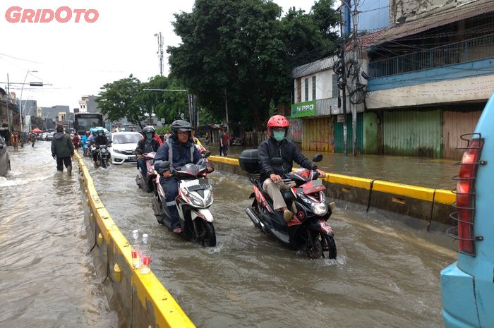 Pengendara motor dan mobil menerobos banjir di Jalan Jatinegara Barat, Jakarta Timur.