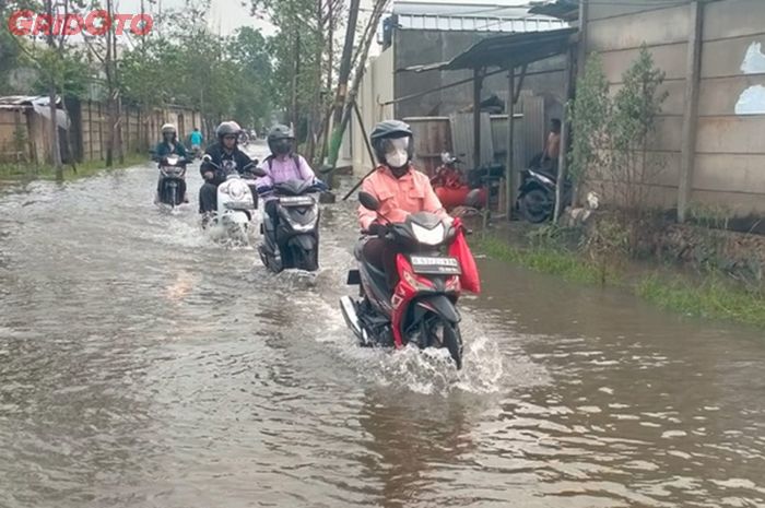 Ilustrasi, pengendara motor melintas di genangan banjir