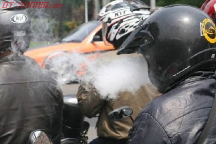 Ilustrasi kebiasaan merokok saat naik motor merupakan tindakan yang berbahaya.