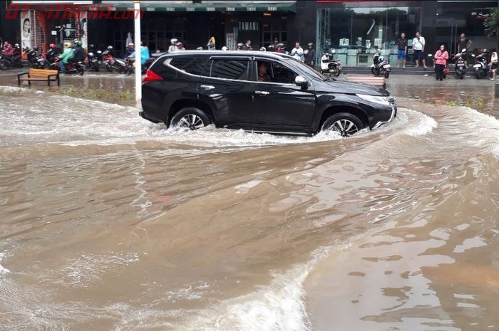 Ilustrasi mobil tengah menerabas genaanan air banjir.