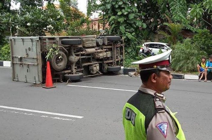 Petugas berjaga di lokasi mobil boks yang terbalik di Jalan Arjuno Surabaya, Jumat (28/12/2018)