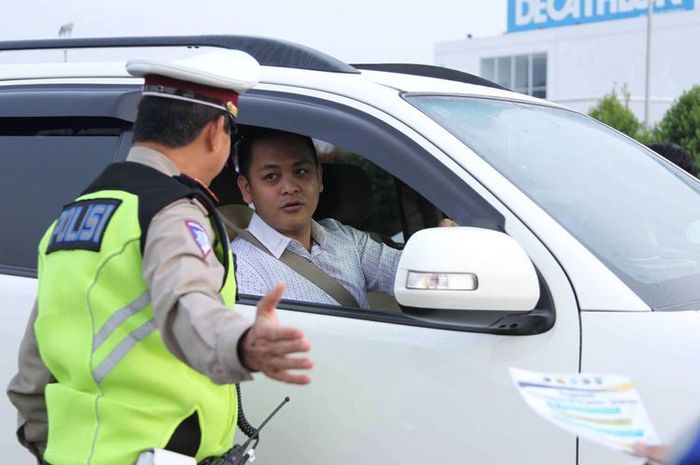 Petugas kepolisian mengarahkan kendaraan yang melintas saat uji coba sistem ganjil genap di Pintu Tol Kunciran 2, Tangerang, Banten, Senin (16/4/2018). 