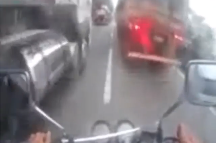 Biker dengan berani menyalip di antara truk-truk besar
