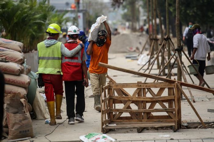 Pekerja menyelesaikan revitalisasi trotoar dan taman di kawasan jalan Sudirman, Jakarta Pusat, Kamis (19/7/2018).