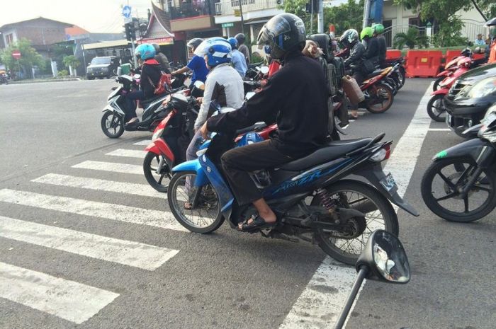 pengendara sepeda motor yang berhenti di marka jalan