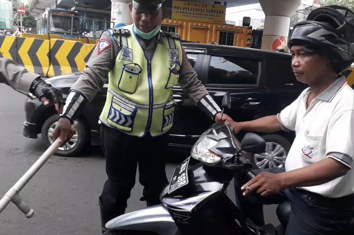 Seorang pengendara motor dihentikan polisi karena kedapatan merokok saat berkendara di kawasan Kampung Melayu, Senin (8/4/2019)