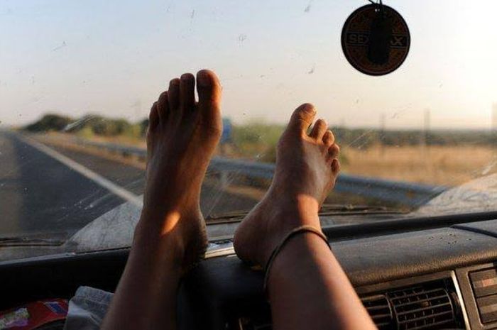 Foto ilustrasi mengangkat kaki di atas dashboard mobil