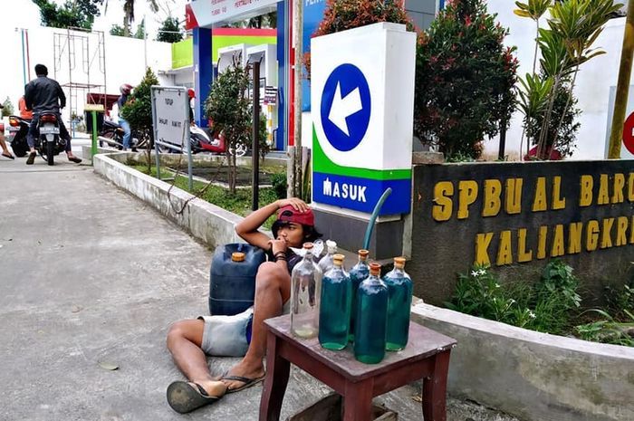 Penjual bensin eceran berjualan di samping SPBU