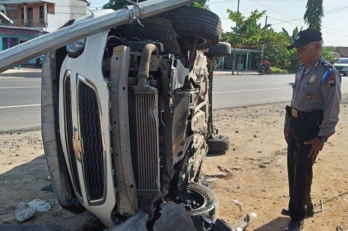 Petugas memeriksa kondisi Chevrolet Spin yang terguling usai menabrak motor dan tiang listrik hingga roboh di Jalan Raya Solo-Wonogiri.