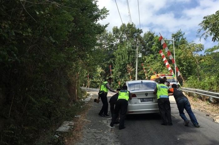 Petugas kepolisian membantu kendaraan yang gagal menanjak di tanjakan Cinopati, Bantul, Yogyakarta.