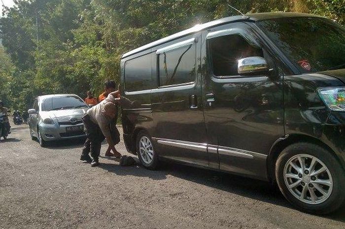 Anggota Polisi Ipda Dalhari bersama rekan-rekan sedang menolong mobil yang gagal nanjak di Cinomati.
