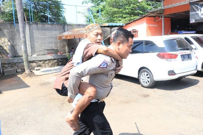 Brigadir Rudi Nurdiansyah, anggota Satlantas Polres Karawang, menggendong seorang kakek yang sempat tertinggal di Rest Area KM 62 tol Jakarta-Cikampek, Minggu (9/6/2019).