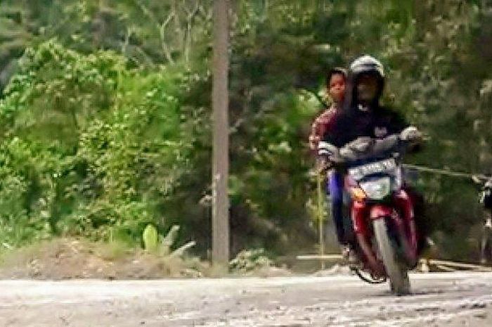 Dua warga berboncengan naik motor melintas di ruas jalan yang aspalnya terkelupas habis di Kecamatan Sitelu Tali Urang Jehe, Kabupaten Pakpak Bharat, Minggu (16/6/2019).