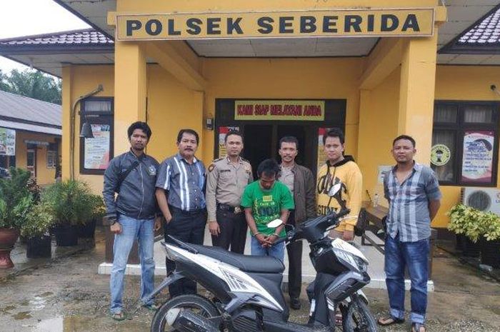 Tersangka DI (tengah) tertunduk saat diamankan sementara di Poksek Seberida, Inhu, bersama barang bukti sepeda motor. 