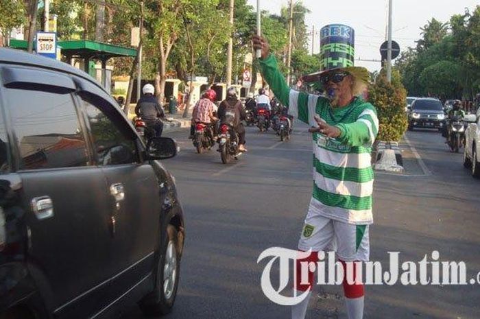 Aksi Edy Riyanto, polisi cepek di depan RSUD Dr Soetomo yang kenakan kostum jersey nyentrik untuk menghibur pengguna jalan saat menjalankan tugasnya. 