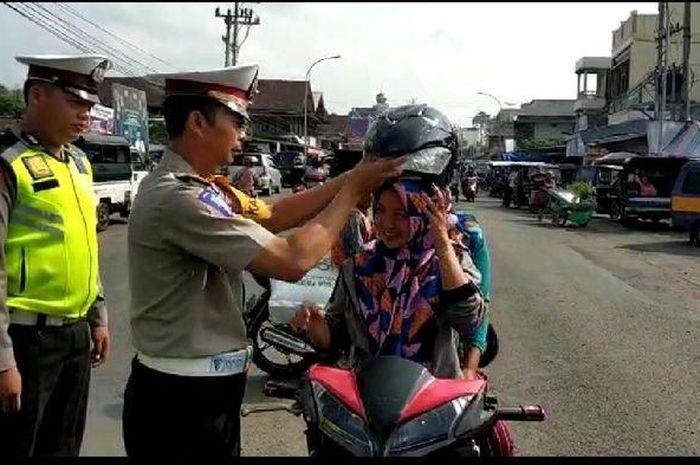 Kasatlantas Iptu M Lubis membagikan helm gratis ke pengendara sepeda motor, yang melintas didepan Mapolres Empatlawang, Rabu (26/6/2019).