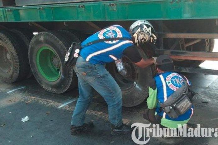 Sebuah truk kontainer diperiksa bagian bawahnya oleh relawan kecelekaan setelah melindas tiga pengendara Vario di Mojokerto