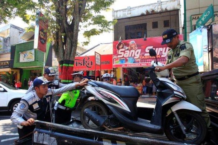 Petugas gabungan mengangkut dua sepeda motor yangmelanggar aturan parkir di Jalan Pemuda, Kota Magelang, Jumat (26/7/2019). 