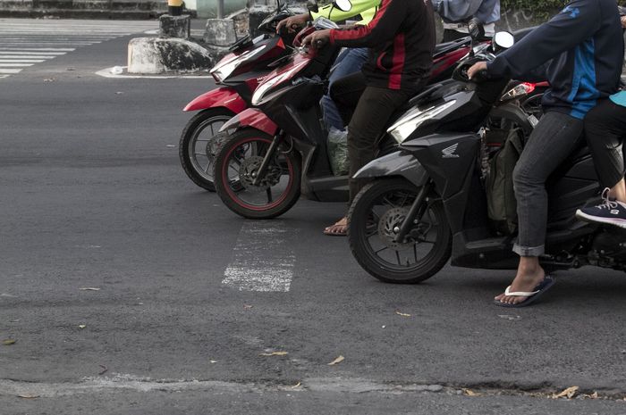 Ilustrasi pengendara motor yang berhenti melewati garis stop pada lampu merah